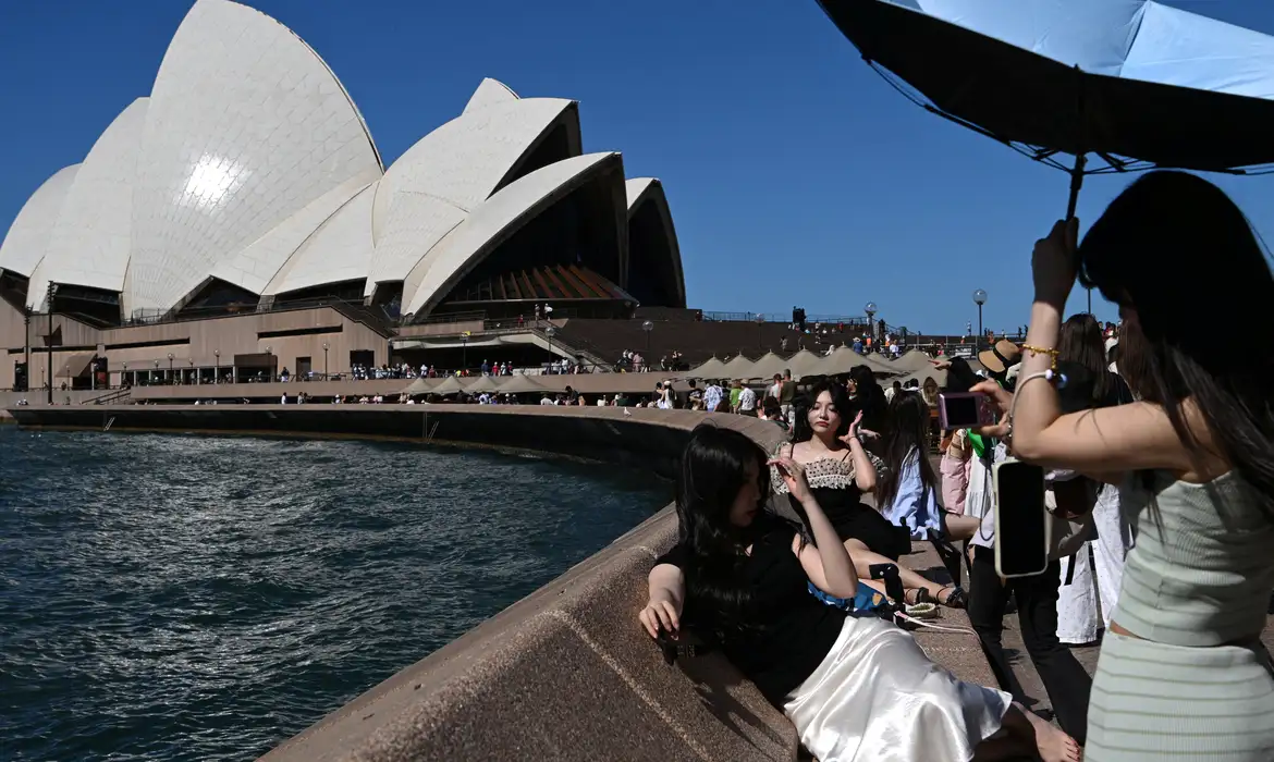 People take pictures near the Sydney Opera House, in Circular Quay, during hot weather in Sydney, Australia, January 27, 2026. REUTERS/Flavio Brancaleone