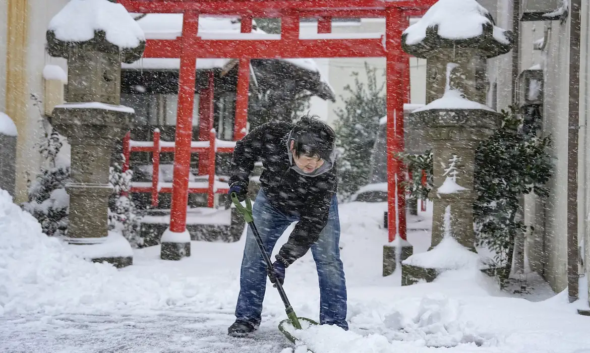 Homem limpa a neve na frente de templo em Tottori, Japão
25/01/2023. Mandatory credit Kyodo/via REUTERS