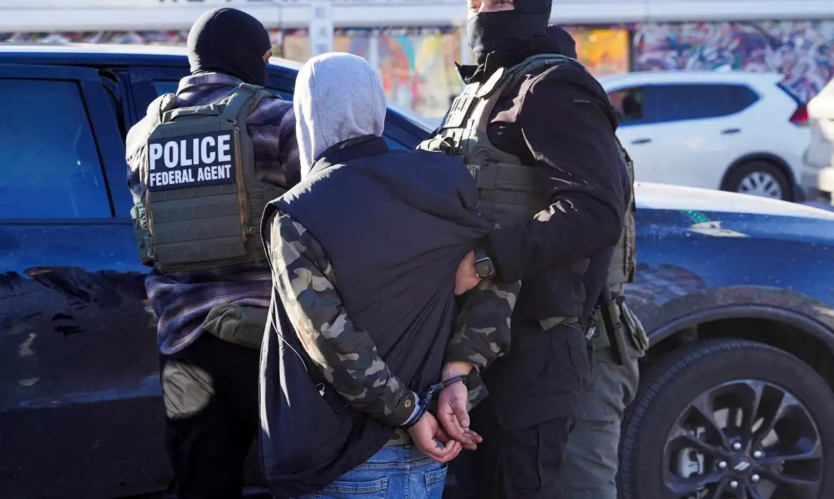 FILE PHOTO: Federal agents detain a person at a bus stop as they conduct an immigration raid days after a U.S. Immigration and Customs Enforcement (ICE) agent fatally shot Renee Nicole Good, in Minneapolis, Minnesota, U.S., January 14, 2026. REUTERS/Ryan Murphy/File Photo