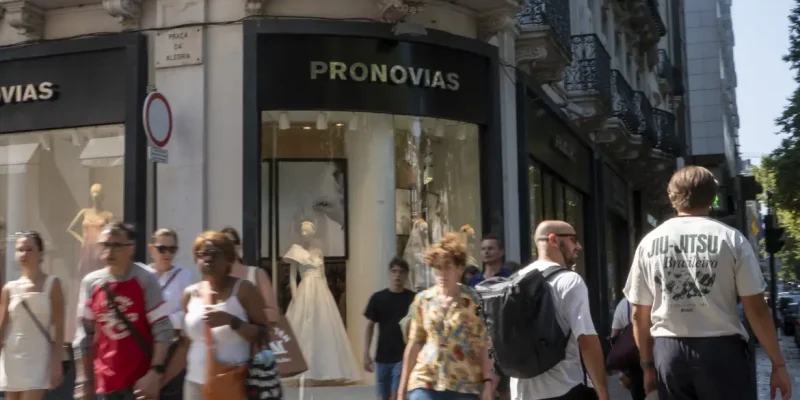 In Lisbon, Portugal, on August 2, 2025, people walk past a Pronovias storefront. The Spanish bridalwear company reports EUR135.9 million in revenue for 2023 and a net loss of EUR128.6 million. In early 2025, Pronovias reduces its capital by EUR193 million and appoints Cristina Alba Ochoa as CEO to lead a new turnaround strategy focused on international growth and financial stabilization by 2027. (Photo by Luis Boza/NurPhoto)NO USE FRANCE