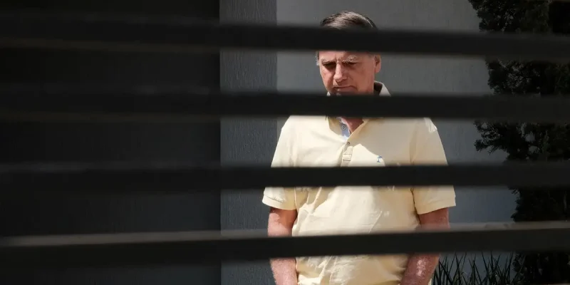 Brazil's former President Jair Bolsonaro stands at his home while under house arrest, amid the final phase of his trial, accused of plotting a coup after his electoral defeat, in Brasilia, Brazil, September 3, 2025. REUTERS/Diego Herculano   REFILE - CORRECTING DATE FROM