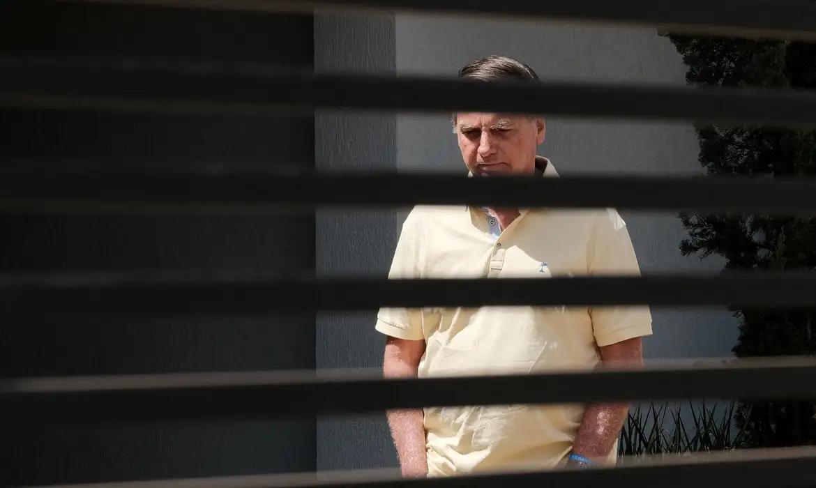 Brazil's former President Jair Bolsonaro stands at his home while under house arrest, amid the final phase of his trial, accused of plotting a coup after his electoral defeat, in Brasilia, Brazil, September 3, 2025. REUTERS/Diego Herculano   REFILE - CORRECTING DATE FROM