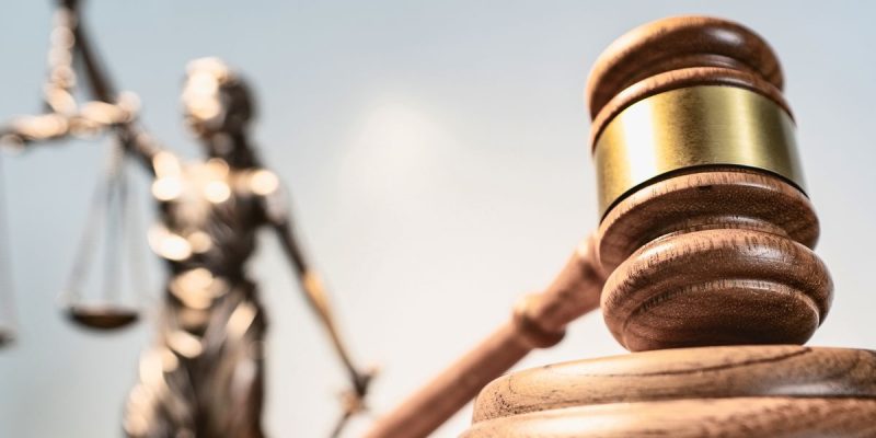 Imagem de uma estatueta da Deusa da Justiça e de um martelo.