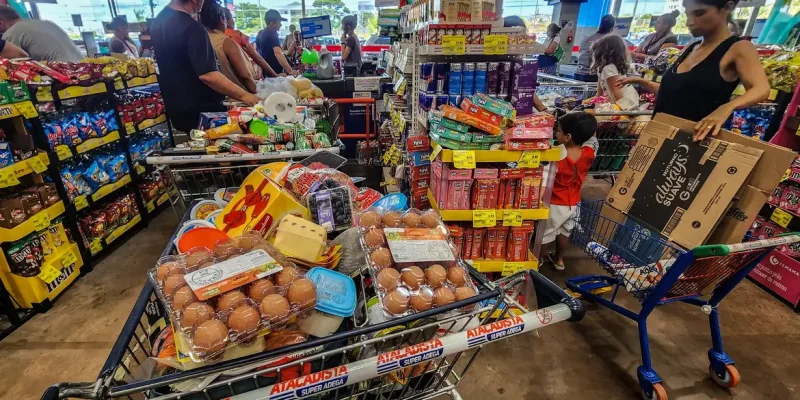 12/06/2026 - Brasília - Consumidores enfrentam longas filas nos caixas de um grande mercado atacadista para finalizar suas compras. Diante do cenário de inflação acumulada e da constante alta de preços nos itens básicos de alimentação, a busca por qualquer tipo de desconto ou promoção tornou-se estratégia essencial para aliviar o orçamento das famílias.Foto: Rafa Neddermeyer/Agência Brasil