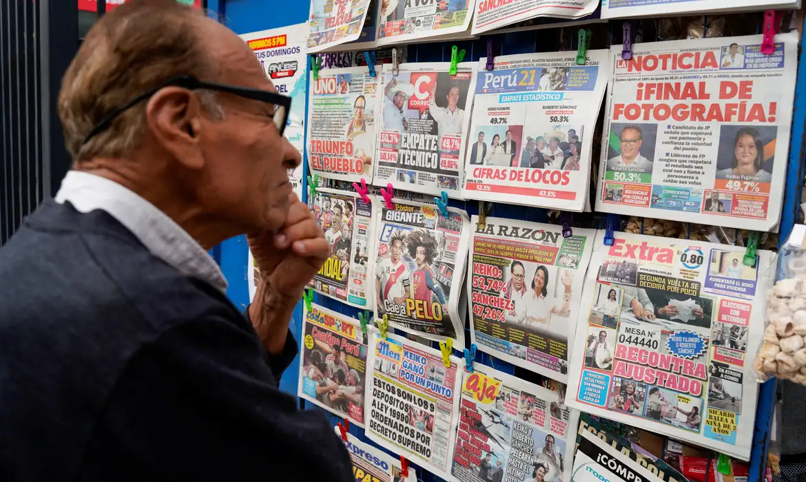 A man looks at a newspaper stand with headlines showing early results of a runoff election between conservative presidential candidate Keiko Fujimori and left-wing candidate Roberto Sanchez, as Fujimori kept a slight lead over Sanchez, with over 90% of the votes counted, according to an official tally, in Lima, Peru, June 8, 2026. REUTERS/Leslie Moreno