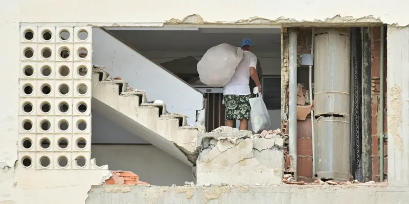 A man carrying belongings walks in a damaged building, after earthquakes hit the country, in La Guaira, Venezuela, June 28, 2026. REUTERS/Maxwell Briceno     TPX IMAGES OF THE DAY