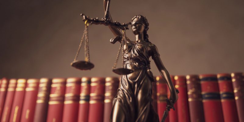 imagem da estatua simbolo da justiça, em frente a livros