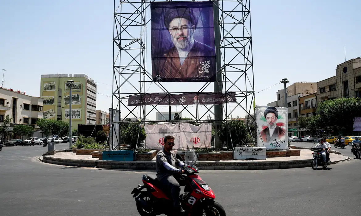 Pessoas passam de motocicleta por um banner com a foto do Líder Supremo do Irã, Mojtaba Khamenei, em Teerã, Irã, em 28 de junho de 2026
Majid Asgaripour/WANA via REUTERS