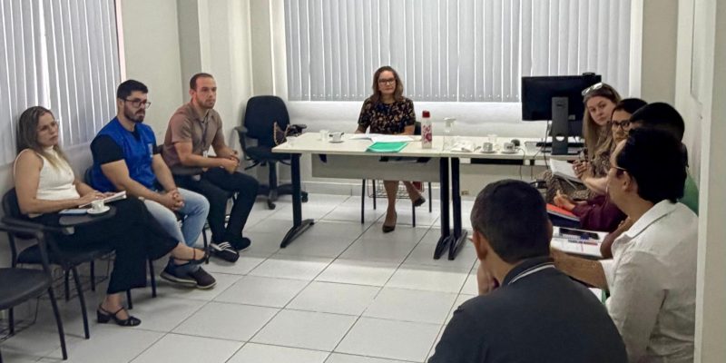 pessoas sentadas em uma sala com a promotora ao centro.