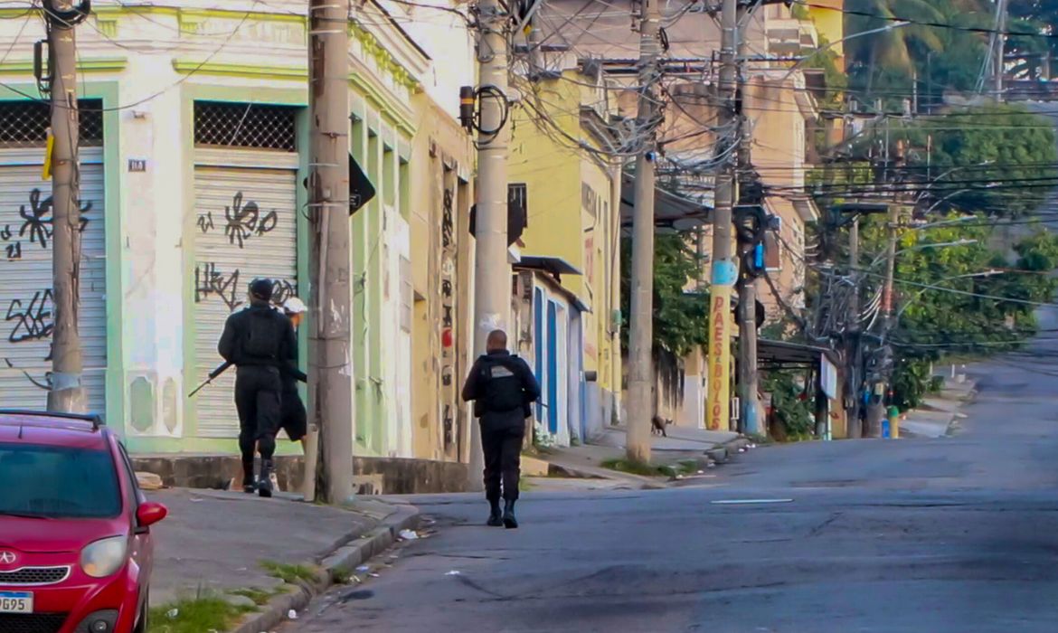 Two armed police officers walk through an almost deserted street in Rio De Janeiro. At least eleven people have died in a police operation against the heads of the Comando Vermelho (Red Command) Criminal organization. (Best possible quality)
