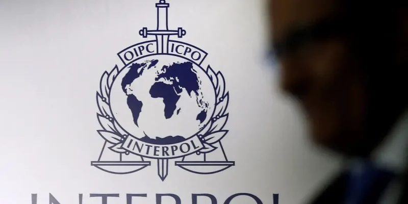 FILE PHOTO: A man passes an Interpol logo during the handing over ceremony of the new premises for Interpol's Global Complex for Innovation, a research and development facility, in Singapore September 30, 2014. REUTERS/Edgar Su//File Photo