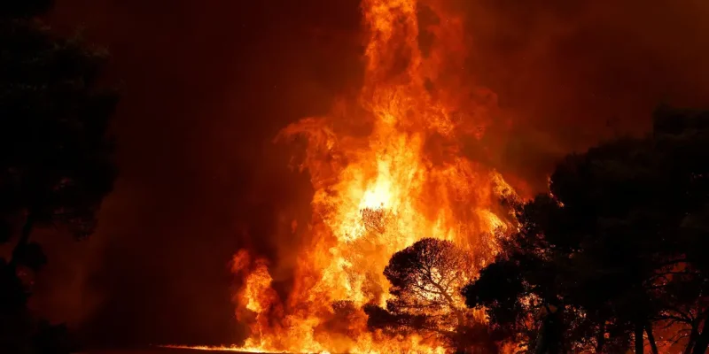 Um homem grava imagens enquanto a fumaça e as chamas se elevam de um incêndio florestal próximo a Agia Paraskevi, na Grécia, em 1º de agosto de 2026. REUTERS/Louisa Gouliamaki/Proibida Reprodução