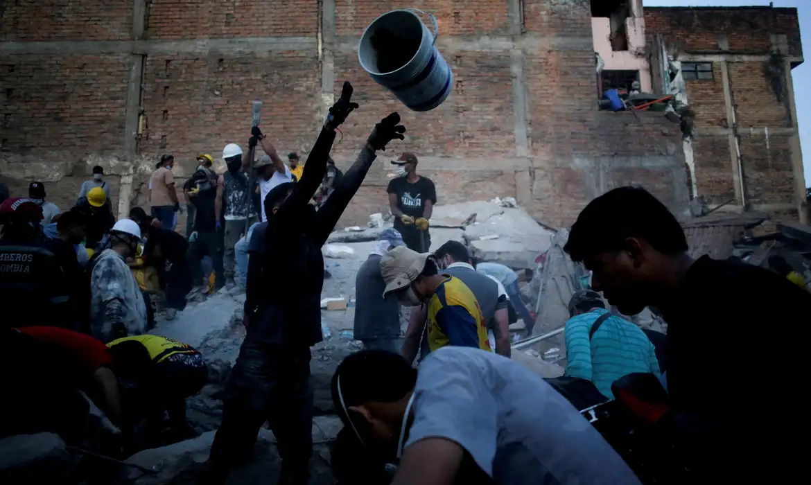 Pessoas recolhem escombros no local onde um prédio ruiu em Pereira, na Colômbia, após o terremoto de segunda-feira. August 11, 2026. REUTERS/Juan David Duque     TPX IMAGES OF THE DAY