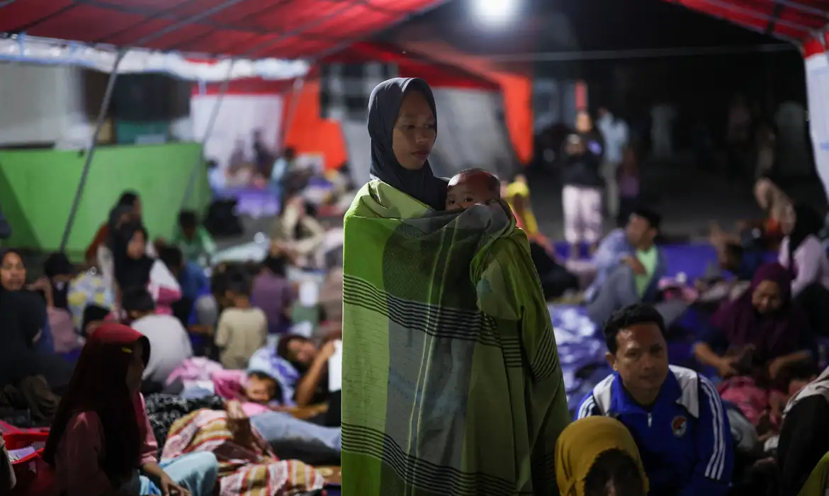 A woman holds a baby as people rest in a shelter at a makeshift evacuation center at a stadium in the aftermath of an earthquake, in Maumere, East Nusa Tenggara, Indonesia, August 16, 2026.  REUTERS/Edgar Su/Proibido Reprodução