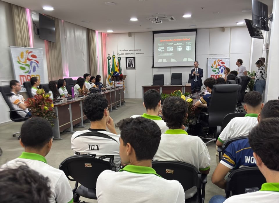 plenário da sede da PGJ com alunos sentados e um promotor falando ao centro