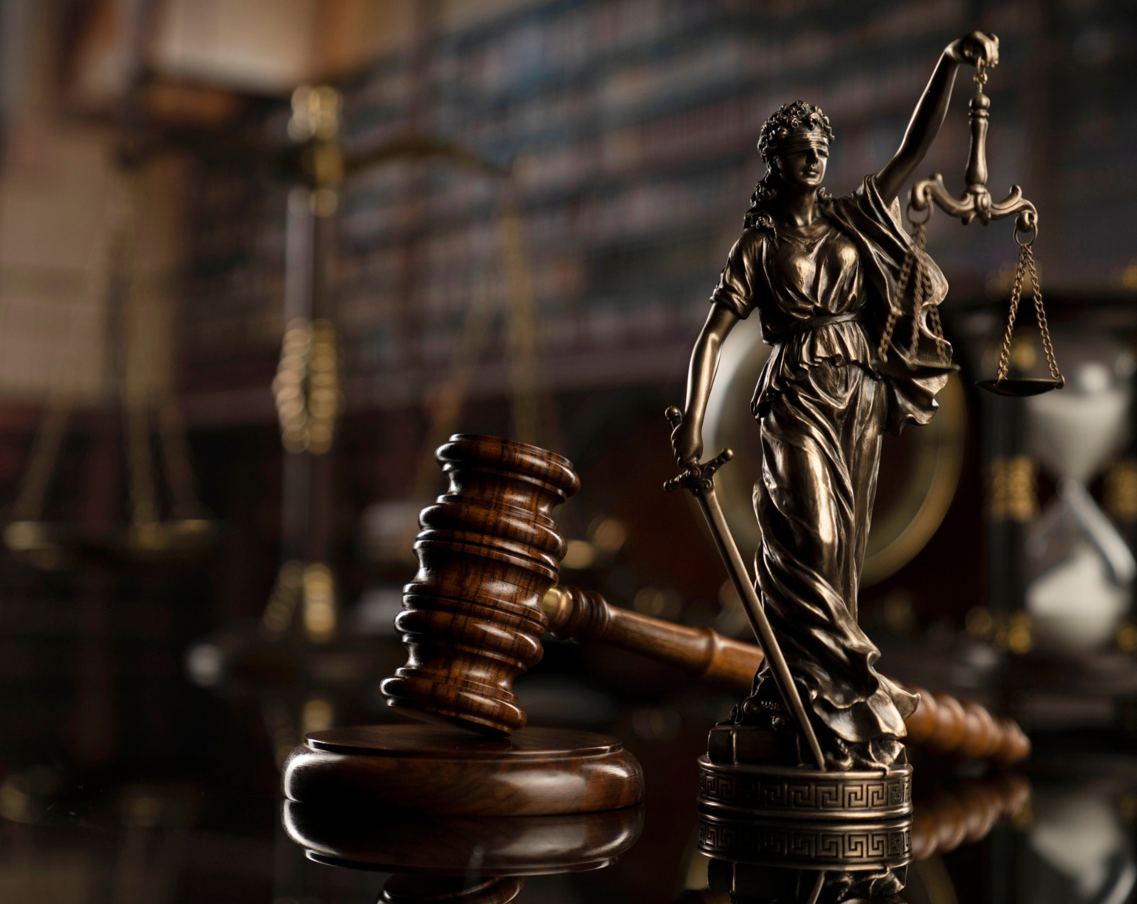 Martelo de madeira da Justiça perto de uma estatua de bronze da Justiça em tamanho pequeno.